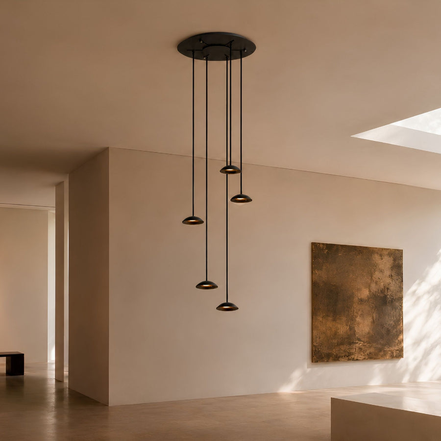 Vue d'ensemble d'une suspension noire à cinq lumières dans un intérieur clair.
