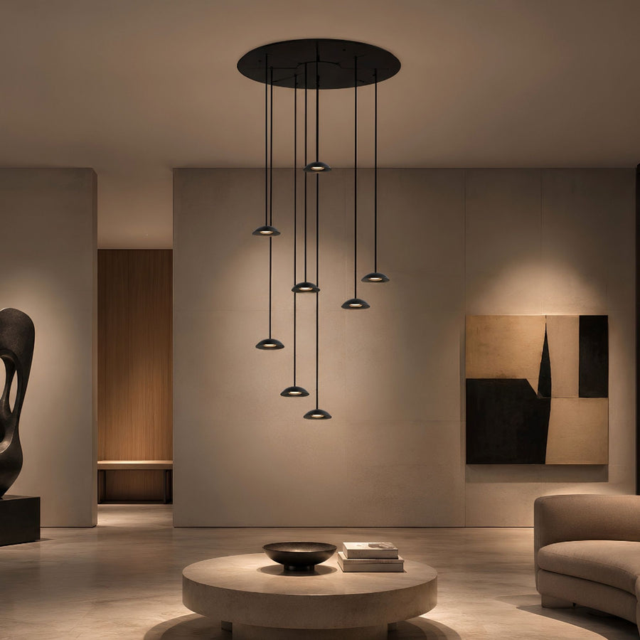 Suspension à huit lumières installée dans un salon contemporain, éclairage tamisé.