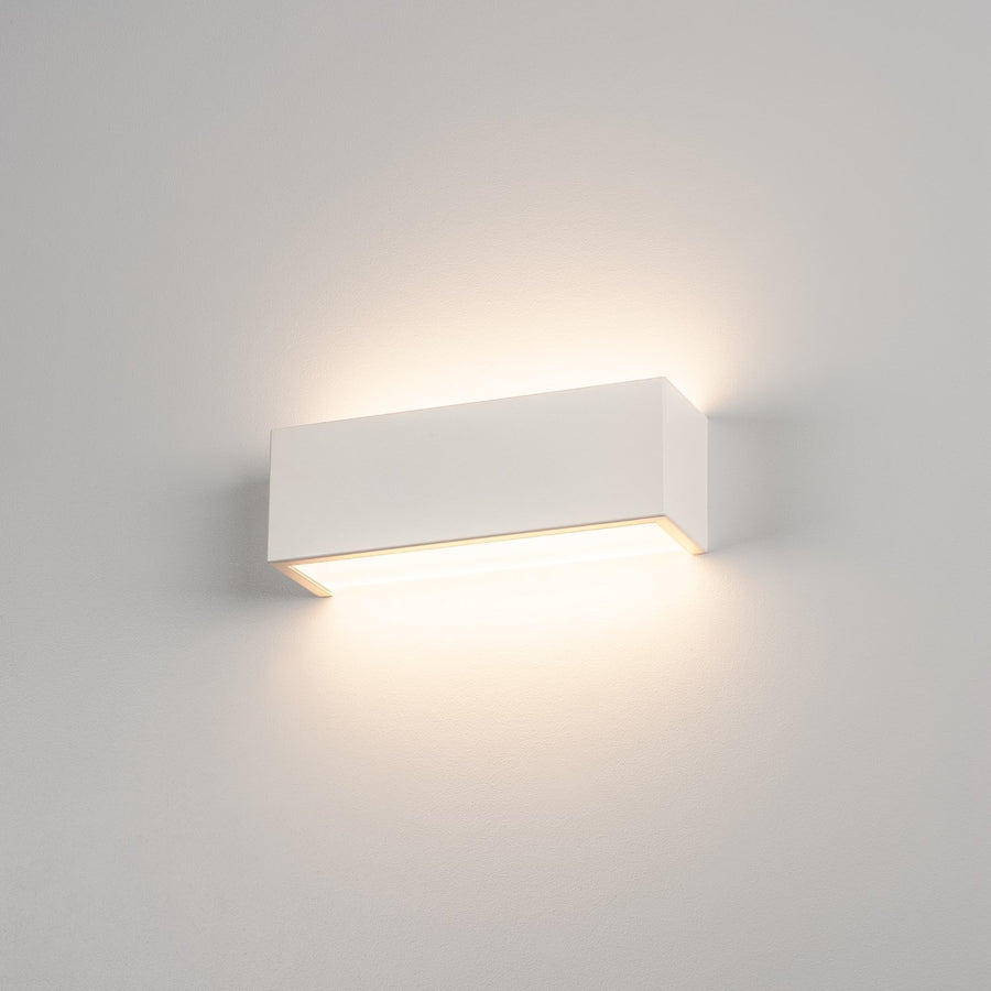 Applique blanche installée sur un mur gris, éclairant la paroi vers le haut et le bas.