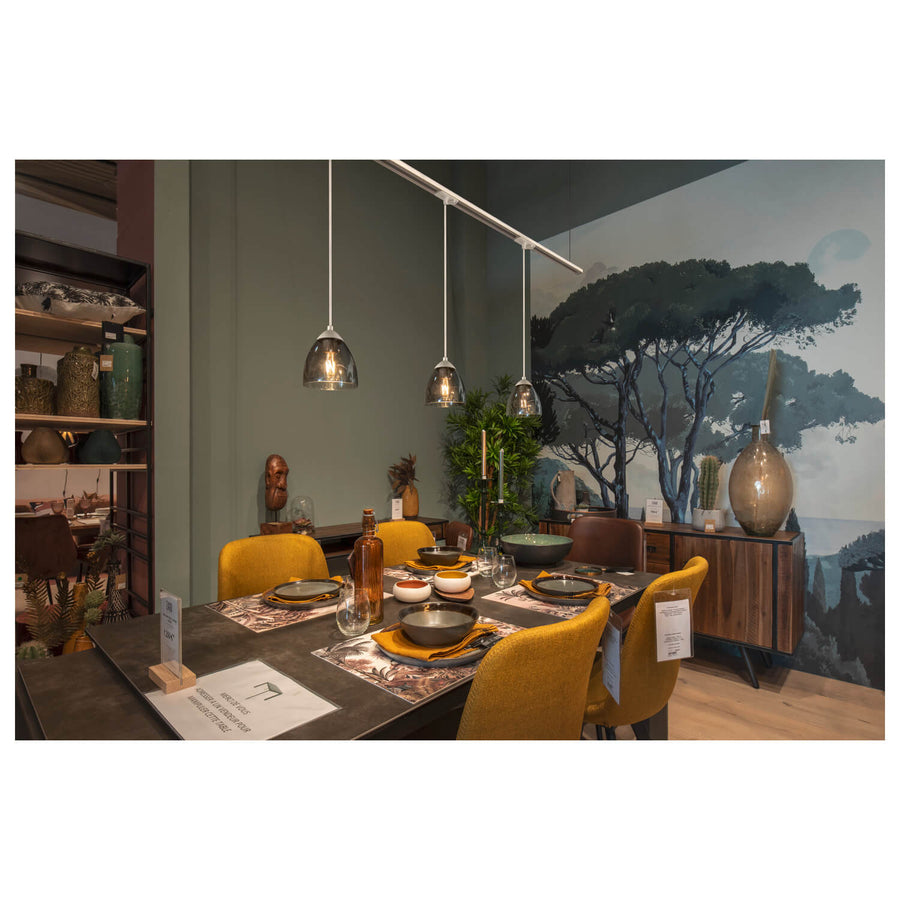 Trois suspensions alignées au-dessus d'une table dressée dans un décor contemporain coloré.