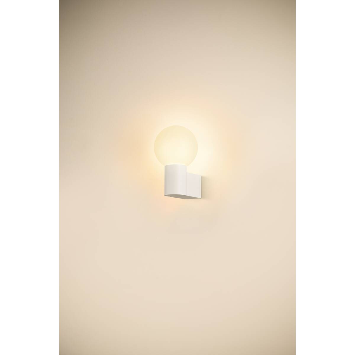 Mise en ambiance de l'applique allumée diffusant une lueur chaude sur le mur