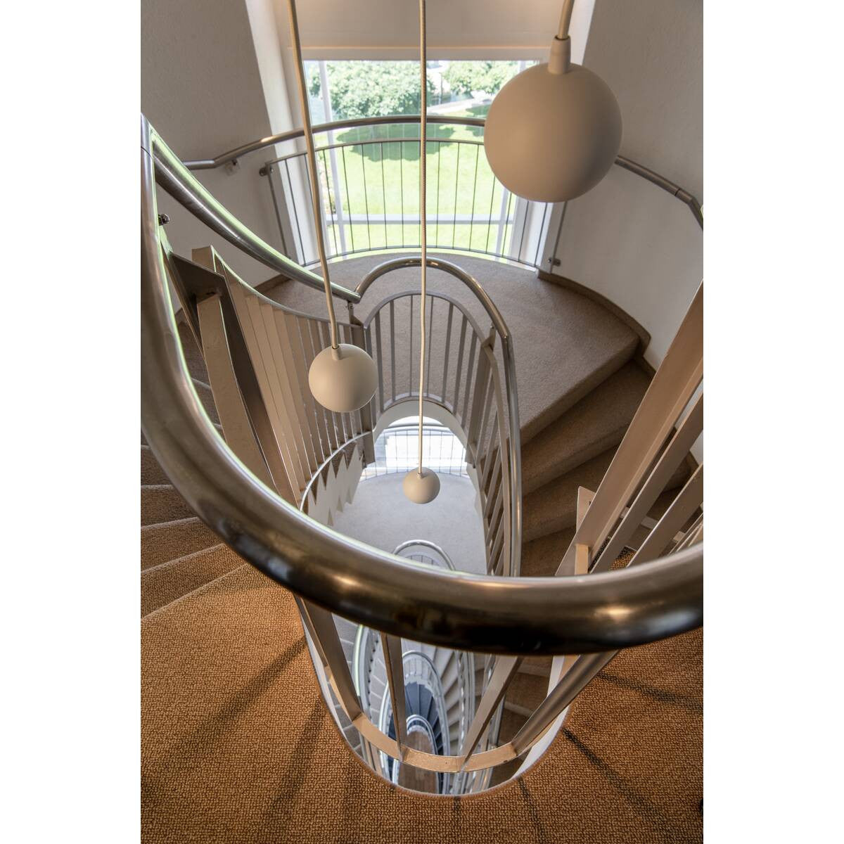 Mise en ambiance dans une cage d’escalier avec plusieurs suspensions boules blanches.