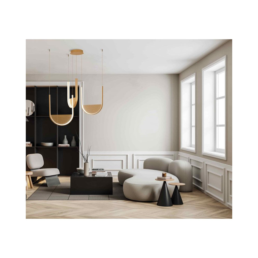 Mise en ambiance dans un salon moderne, suspension dorée au-dessus canapé courbe et bibliothèque noire.