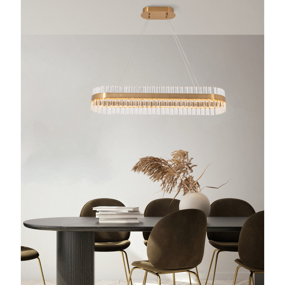 Luminaire suspendu éclairant une table ovale sombre avec vase de fleurs séchées