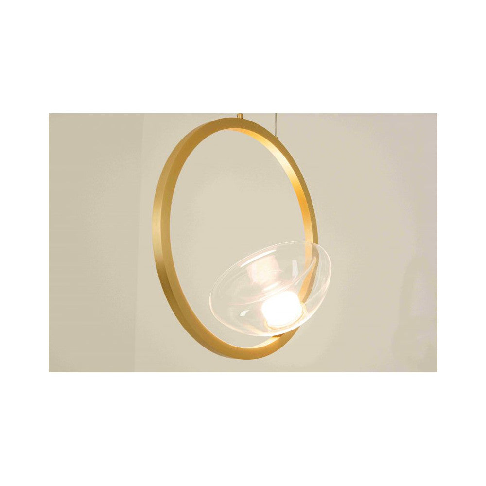 Gros plan de l'anneau doré et de la coupelle en verre éclairée, finition mate et lumineuse.