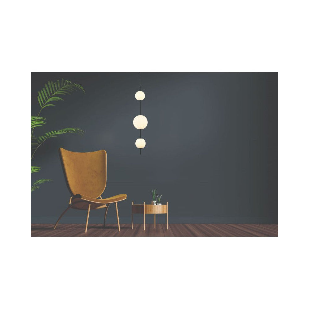 Mise en ambiance salon sombre avec suspension allumée, fauteuil jaune et plante verte.