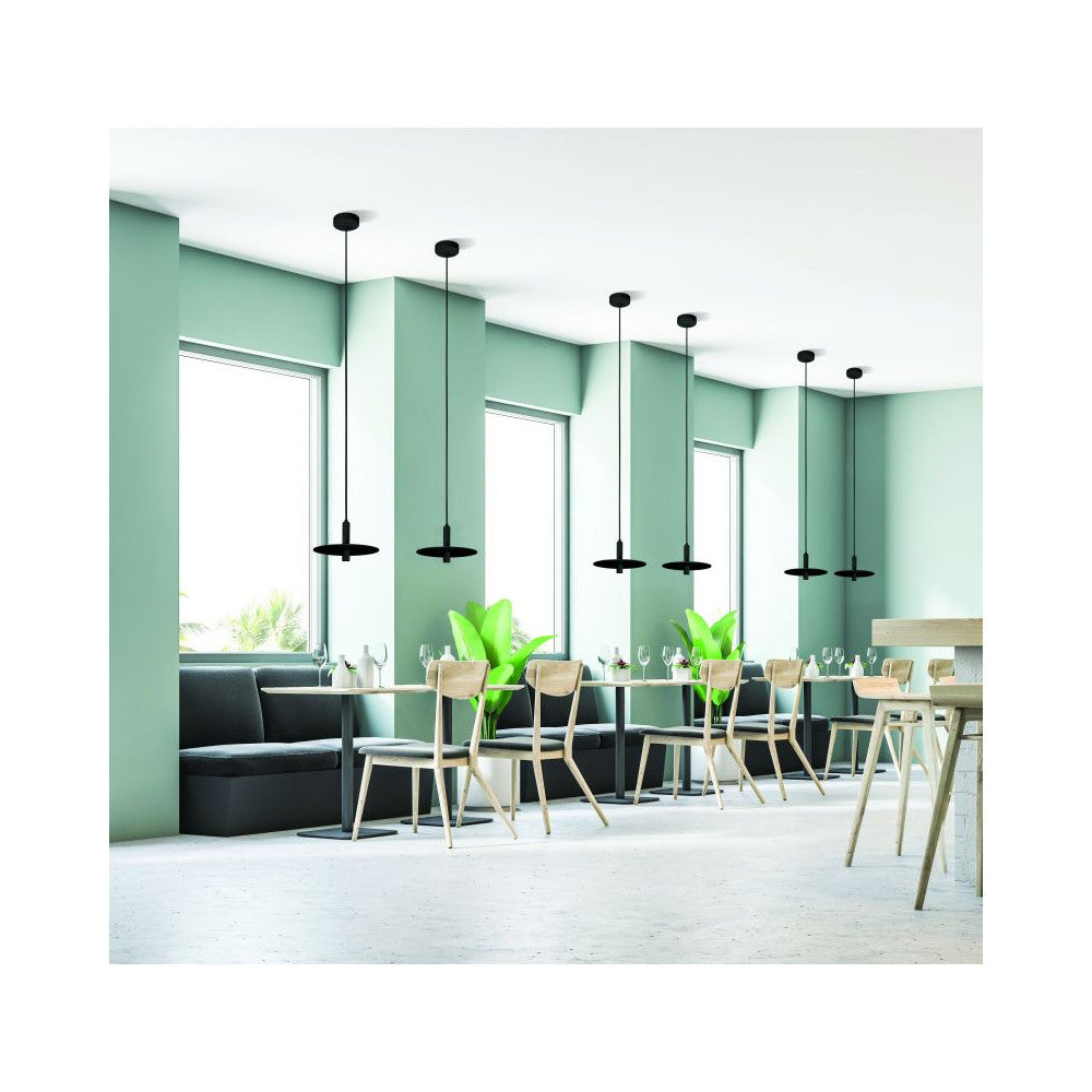 Mise en ambiance dans un café : plusieurs suspensions noires alignées au-dessus de tables.
