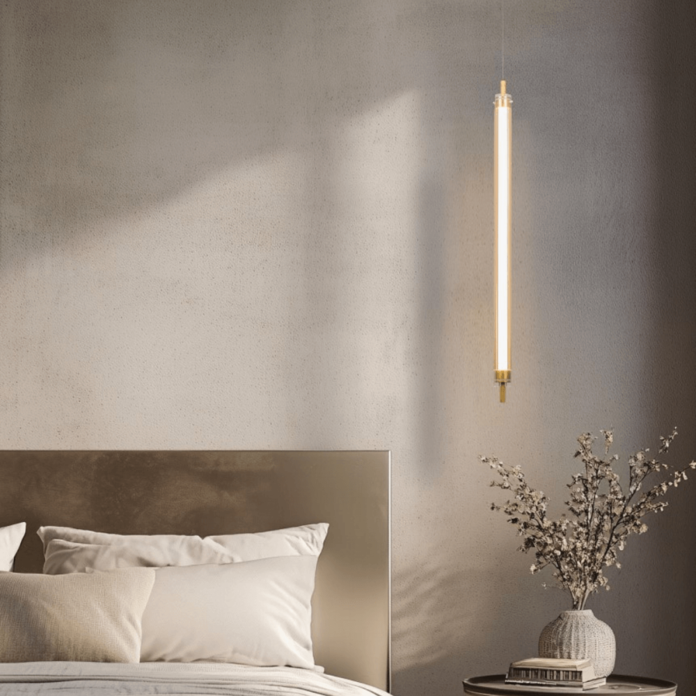 Mise en ambiance chambre, suspension allumée près du lit devant un mur gris