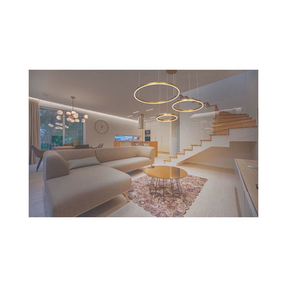 Vue en situation dans un salon moderne, suspension anneaux dorés au-dessus d'une table basse.