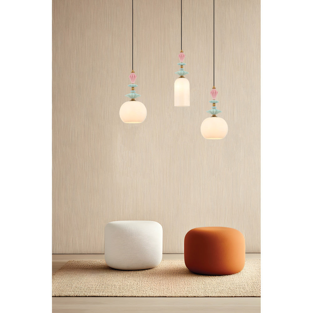Mise en ambiance avec trois suspensions allumées devant un mur beige et deux poufs