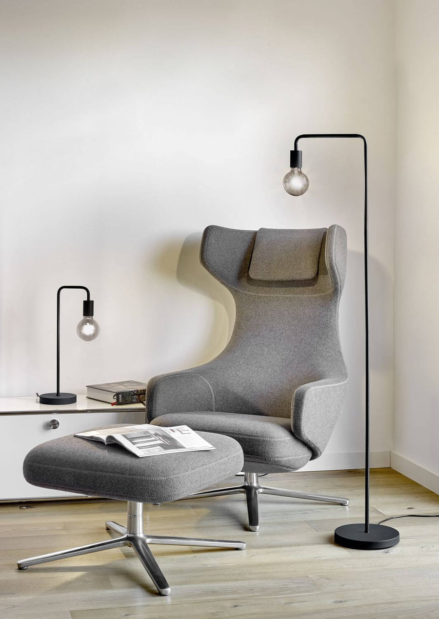 Lampadaire noir mat installé près d'un fauteuil gris dans un salon clair