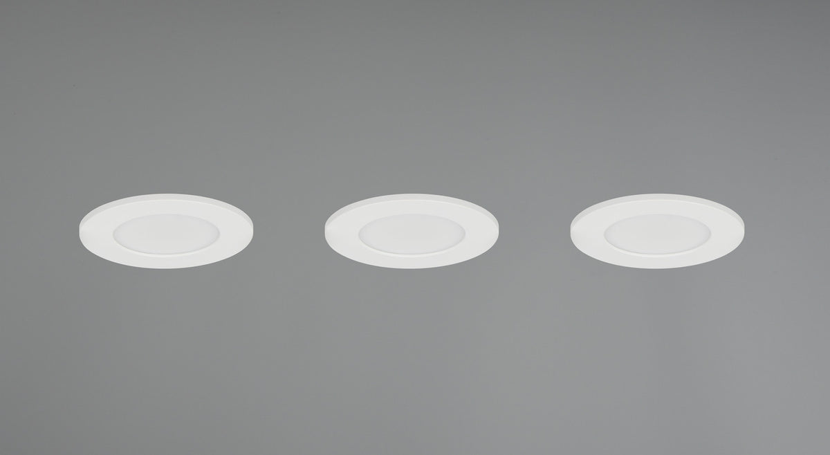 Trois spots encastrés allumés dans un plafond gris, halo lumineux diffus