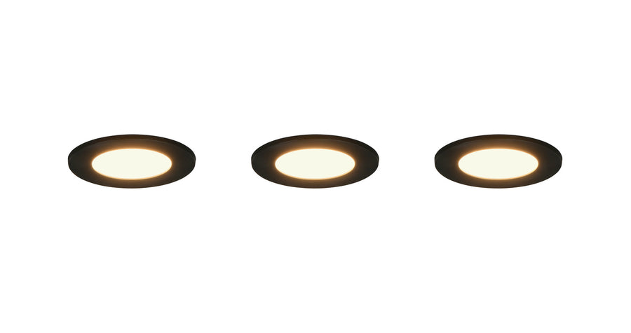 Trois spots encastrables noirs allumés diffusant une lumière chaude sur fond blanc