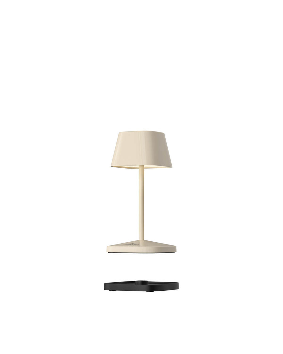 Lampe beige détachée de sa base noire de recharge, vue de face