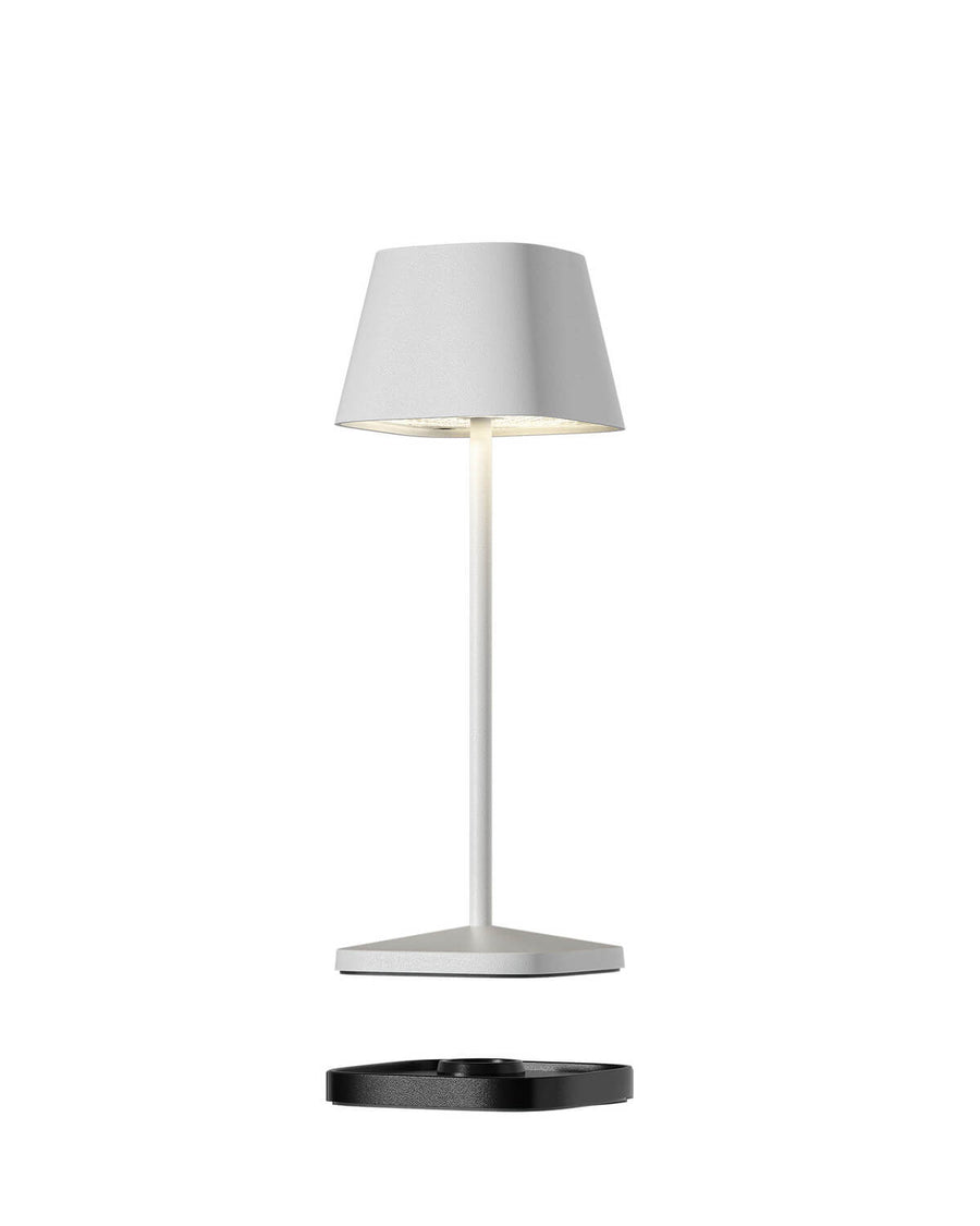 Vue de profil montrant la lampe blanche et sa base de recharge noire détachée.