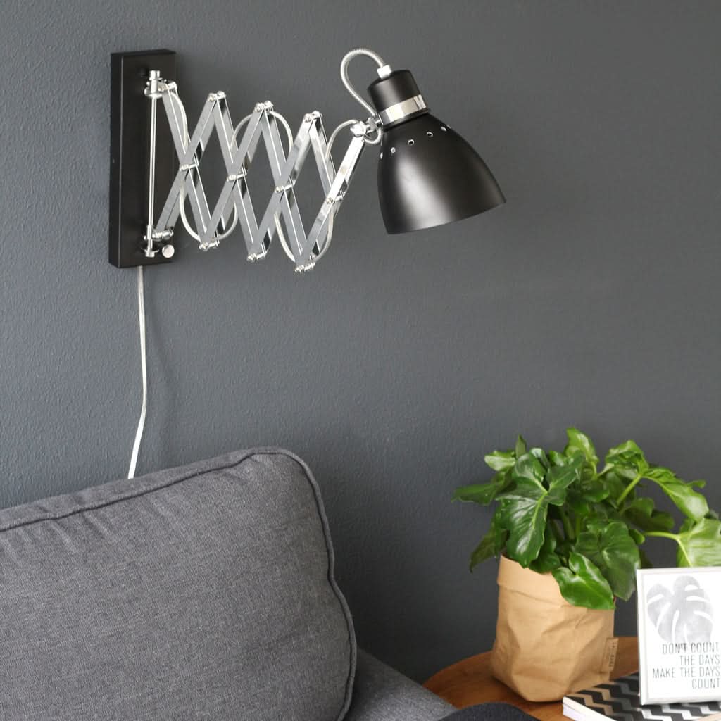 Mise en ambiance de l'applique fixée au mur gris, près d'un canapé et d'une plante