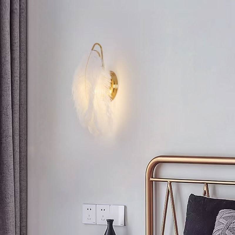 Applique murale en plumes allumée dans une chambre près d'une tête de lit dorée